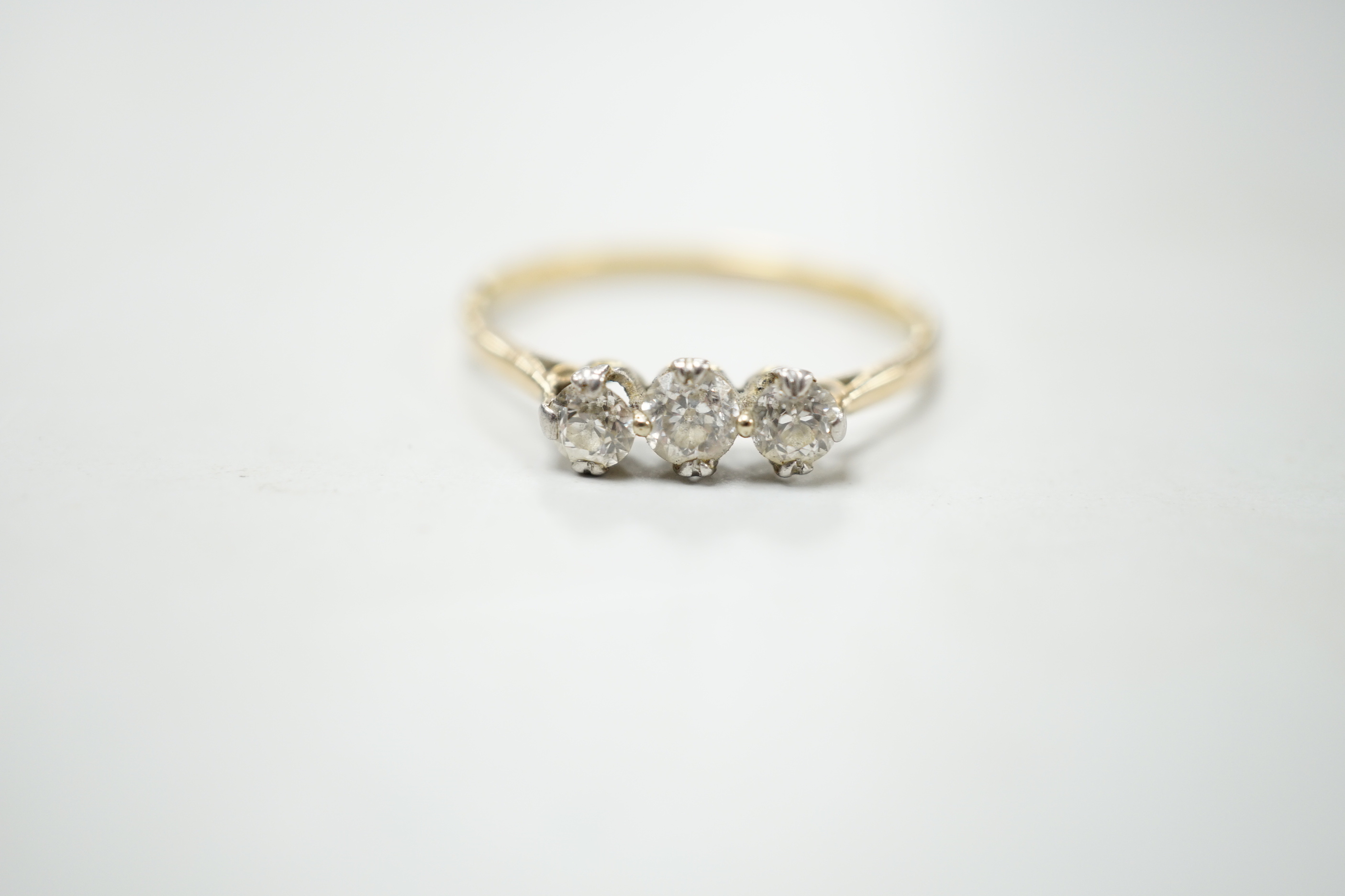 A yellow metal and three stone diamond set ring, size S/T, gross weight 2.1 grams.